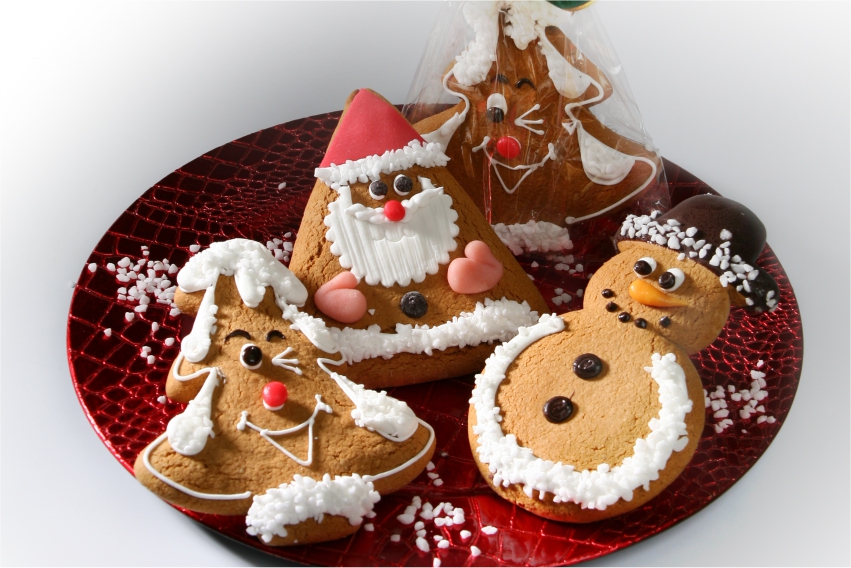 Ein Lebkuchen in Form eines Weihnachtsbaumes mit einem Smily darauf, außerdem ein Schneemann-Lebkuchen und ein Weihnachtsmann-Lebkuchen, dekoriert mit Zuckerstreuseln und verschiedenfarbiger Glasur
