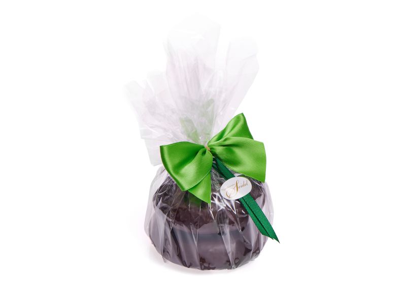 Ein kleiner zweireihiger Baumkuchen in einer Folienverpackung mit grüner Schleife und einem Aufkleber auf der Schleife der das Logo der Kreationen Seidel zeigt.